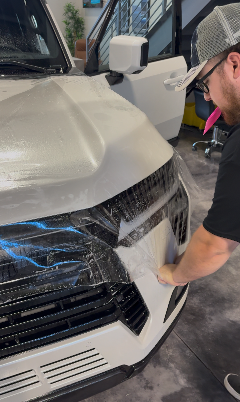 Paint protection film being applied to a hood
