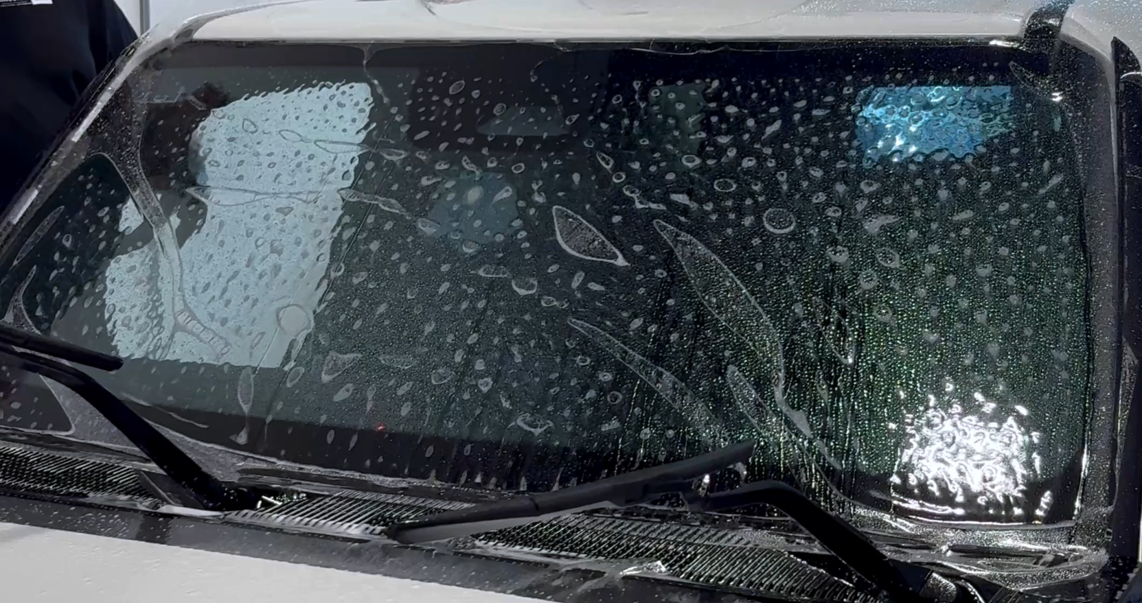Rain beading tightly across a windshield treated with protection film