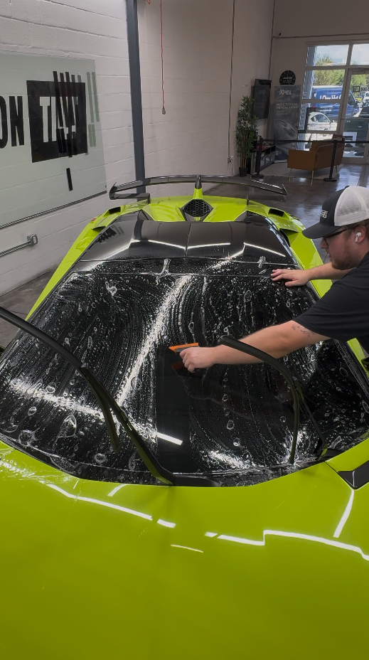 Paint protection film being applied to a sports car hood