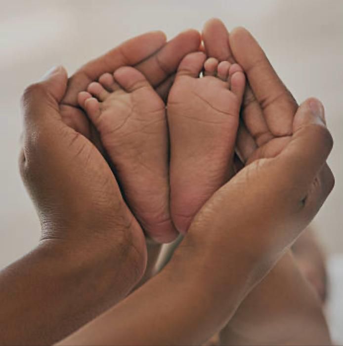 Parent's hands cradling a newborn's feet