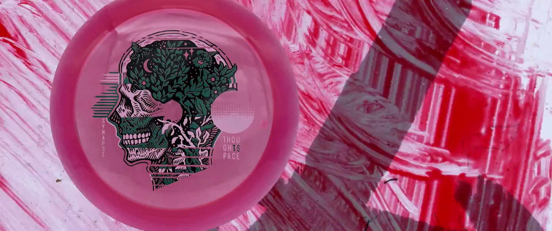A branded pink Thought Space disc and graphic artwork on a white surface.
