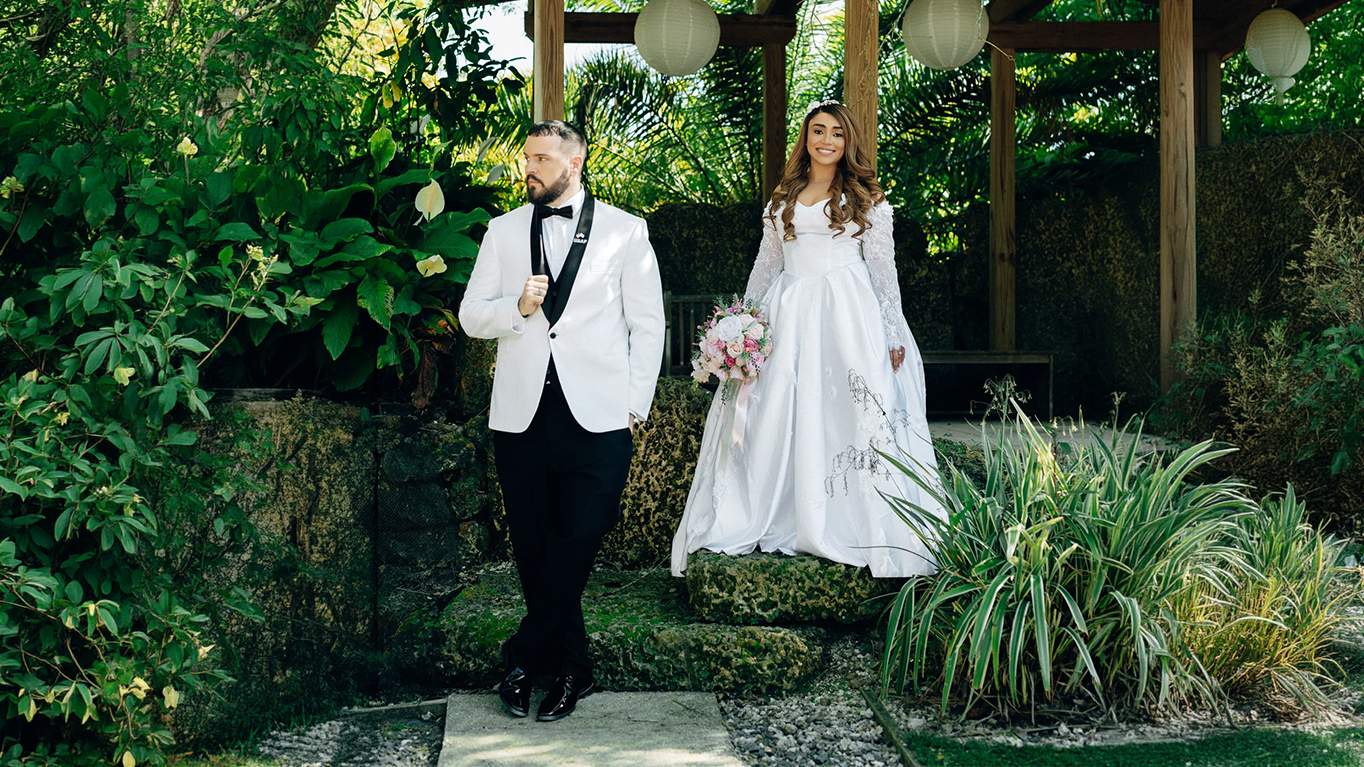 Smiling bride and groom together in a lush garden gazebo