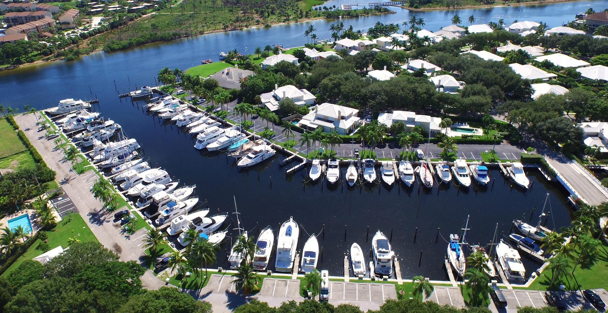 Aerial view of Cypress Island Marina on a sunny day, boats in their slips along curved docks with homes and palm trees behind them