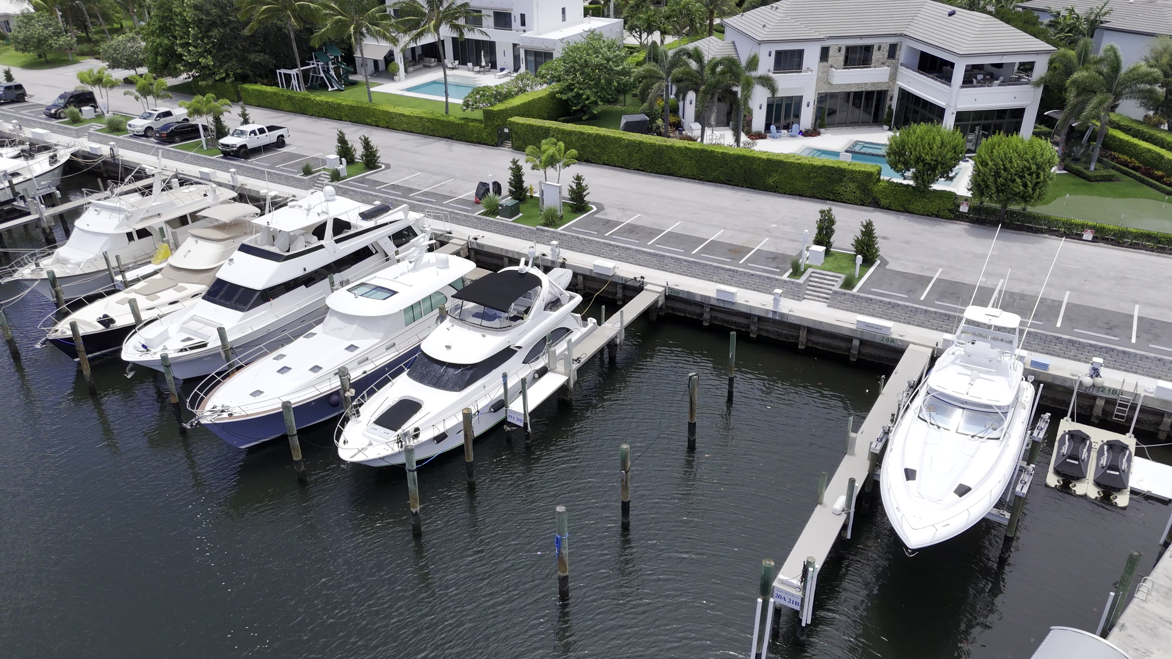 Sportfishing boats and cruisers tied up in their slips along the concrete dock, with parking near the docks
