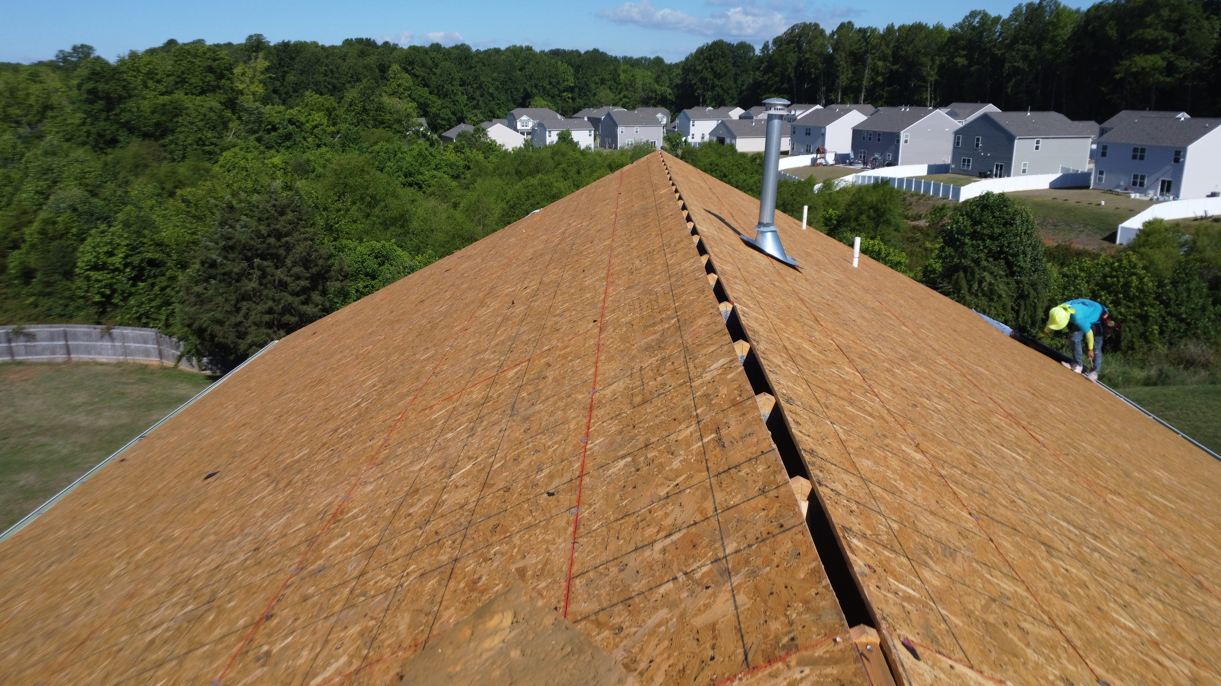 Close-up aerial view of a residential roof with newly installed plywood decking during a roofing renovation project