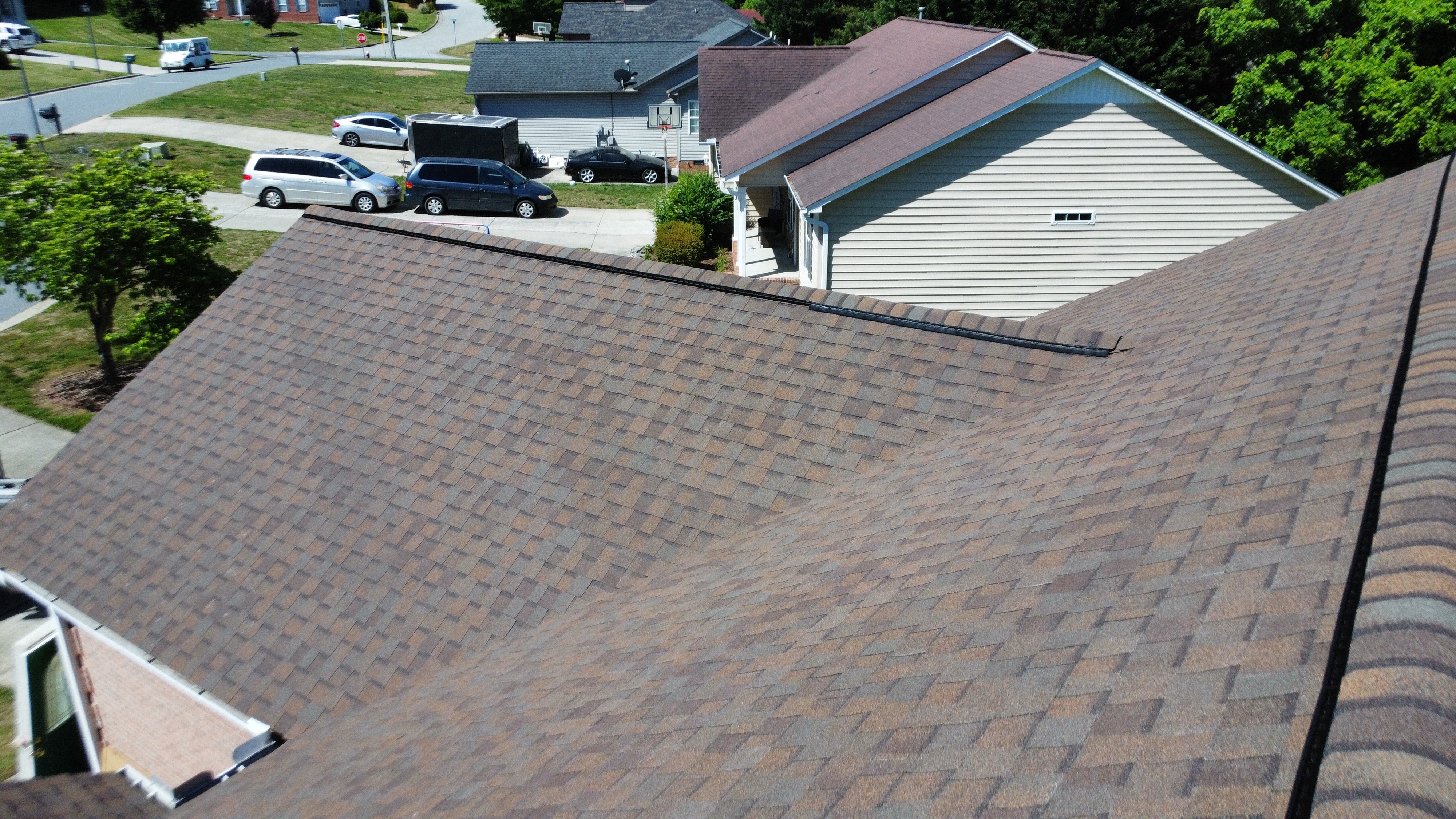 Professional roofers working on a residential roof replacement with safety equipment and construction tools.