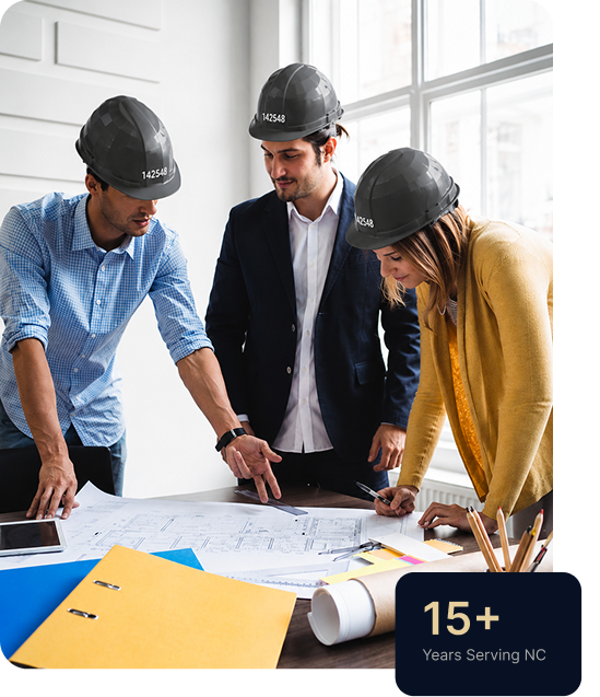 Construction team reviewing architectural blueprints in an office, wearing safety helmets and planning a building project, with 15+ years of service in North Carolina highlighted.