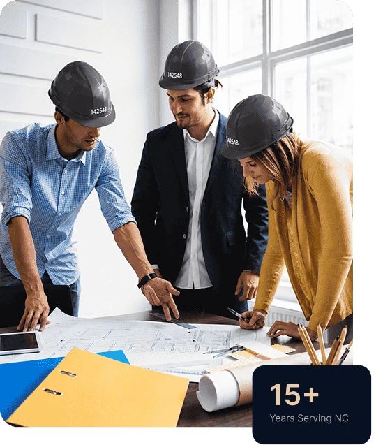 Construction team reviewing architectural blueprints in an office, wearing safety helmets and planning a building project, with 15+ years of service in North Carolina highlighted.