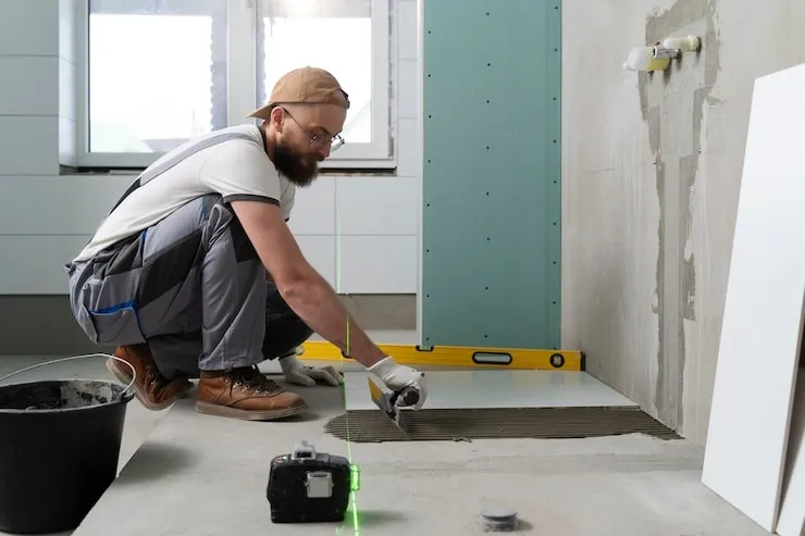 Bathroom installer laying floor tiles.