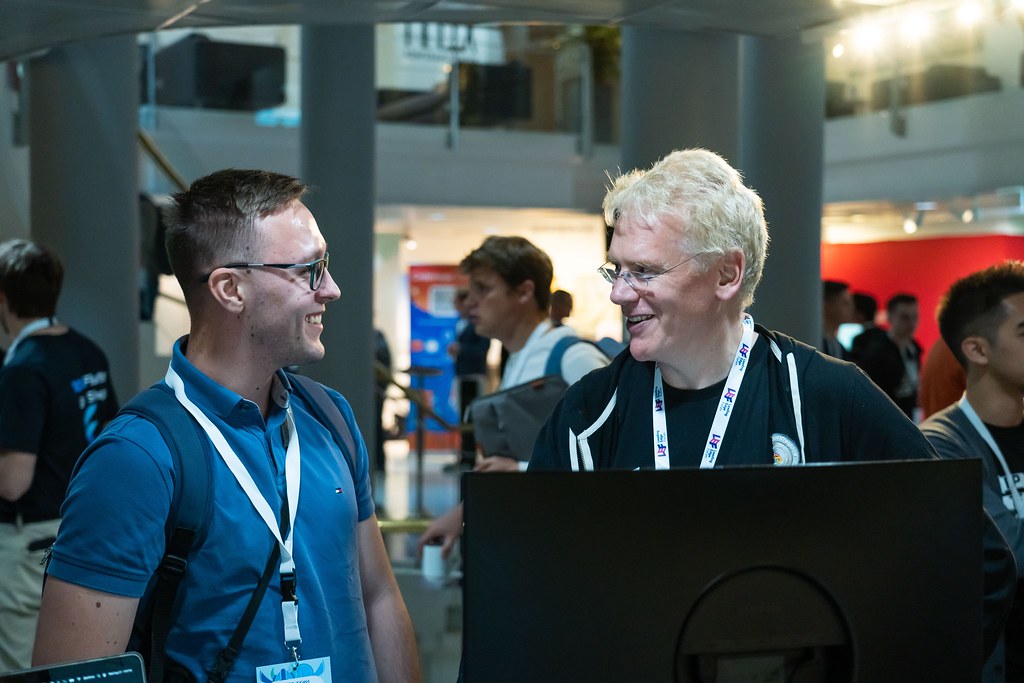 Two conference attendees sharing a laugh in the exhibition hall at a tech event