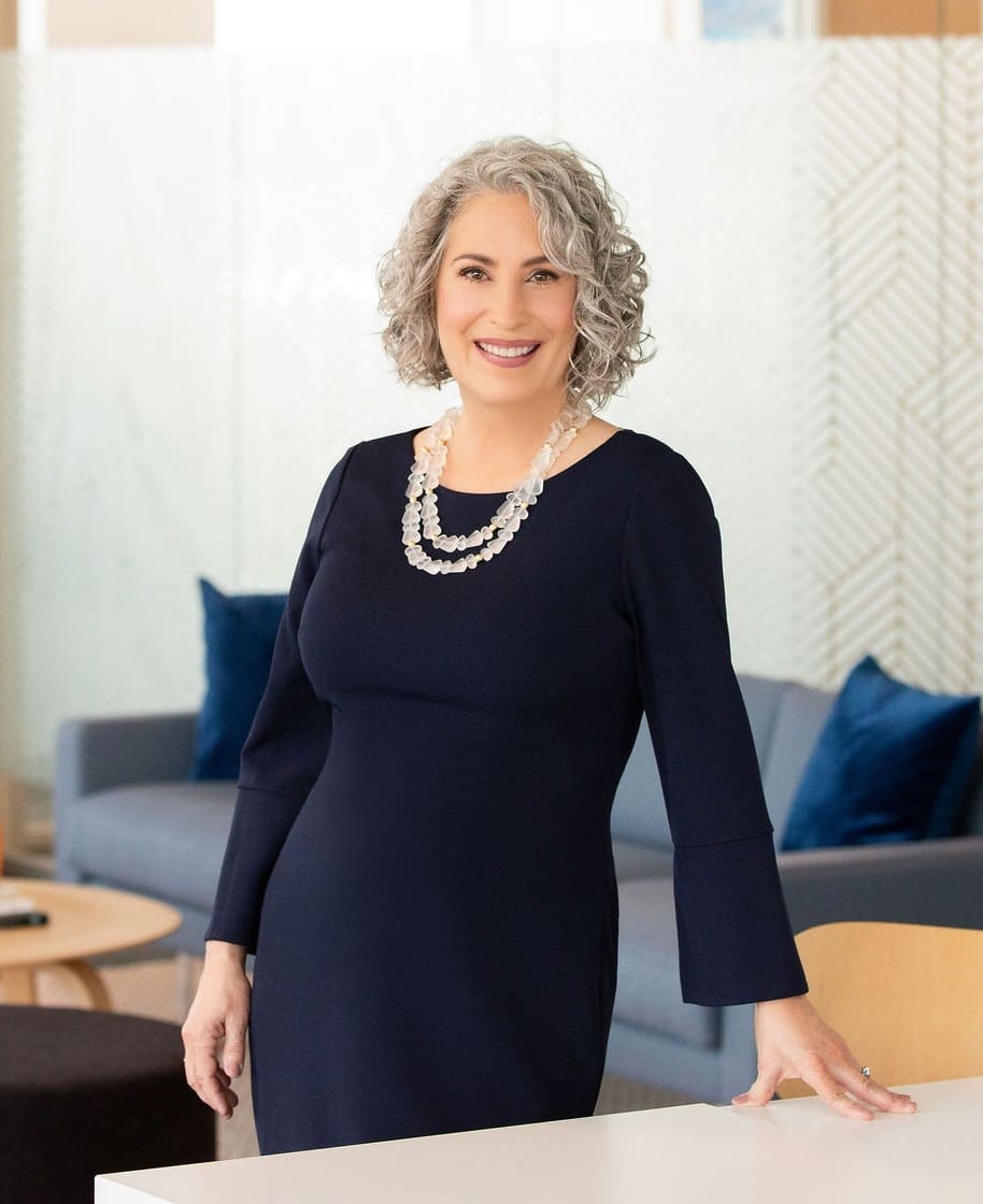 Professional woman with curly gray hair standing and smiling