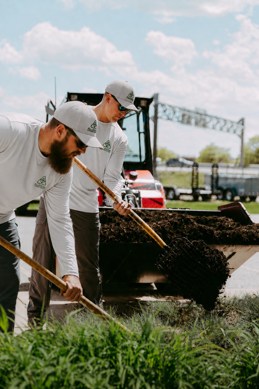 All States Landscaping crew shoveling fresh mulch into planting beds