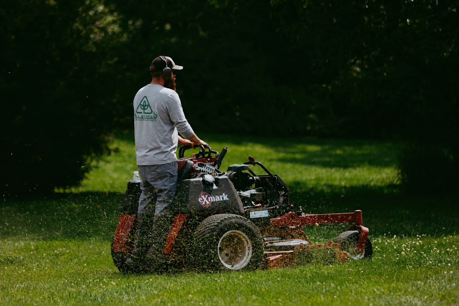 All States Landscaping crew member mowing on a stand-on mower