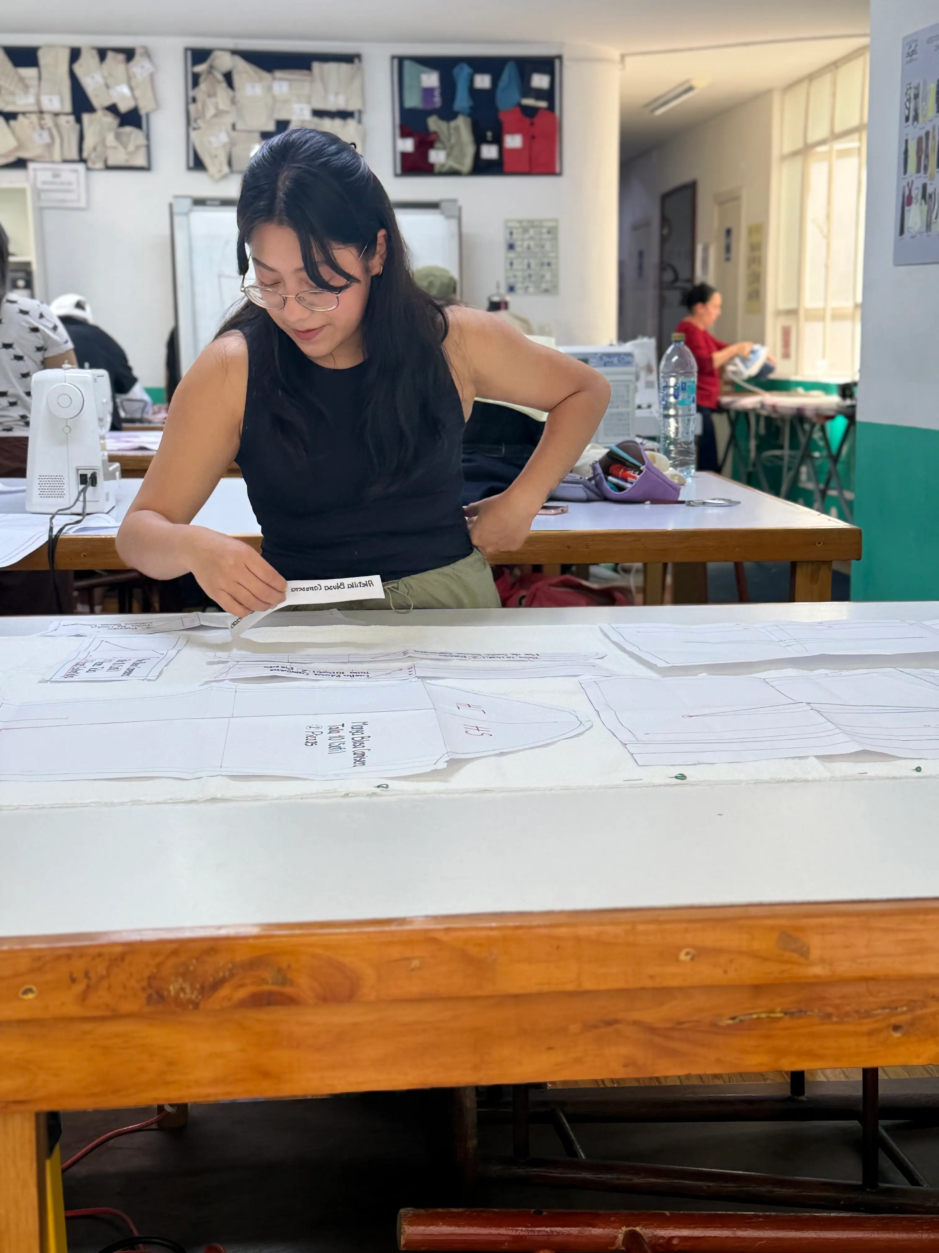 Mujer emprendedora trabajando en su propio taller de costura, cortando tela sobre una mesa