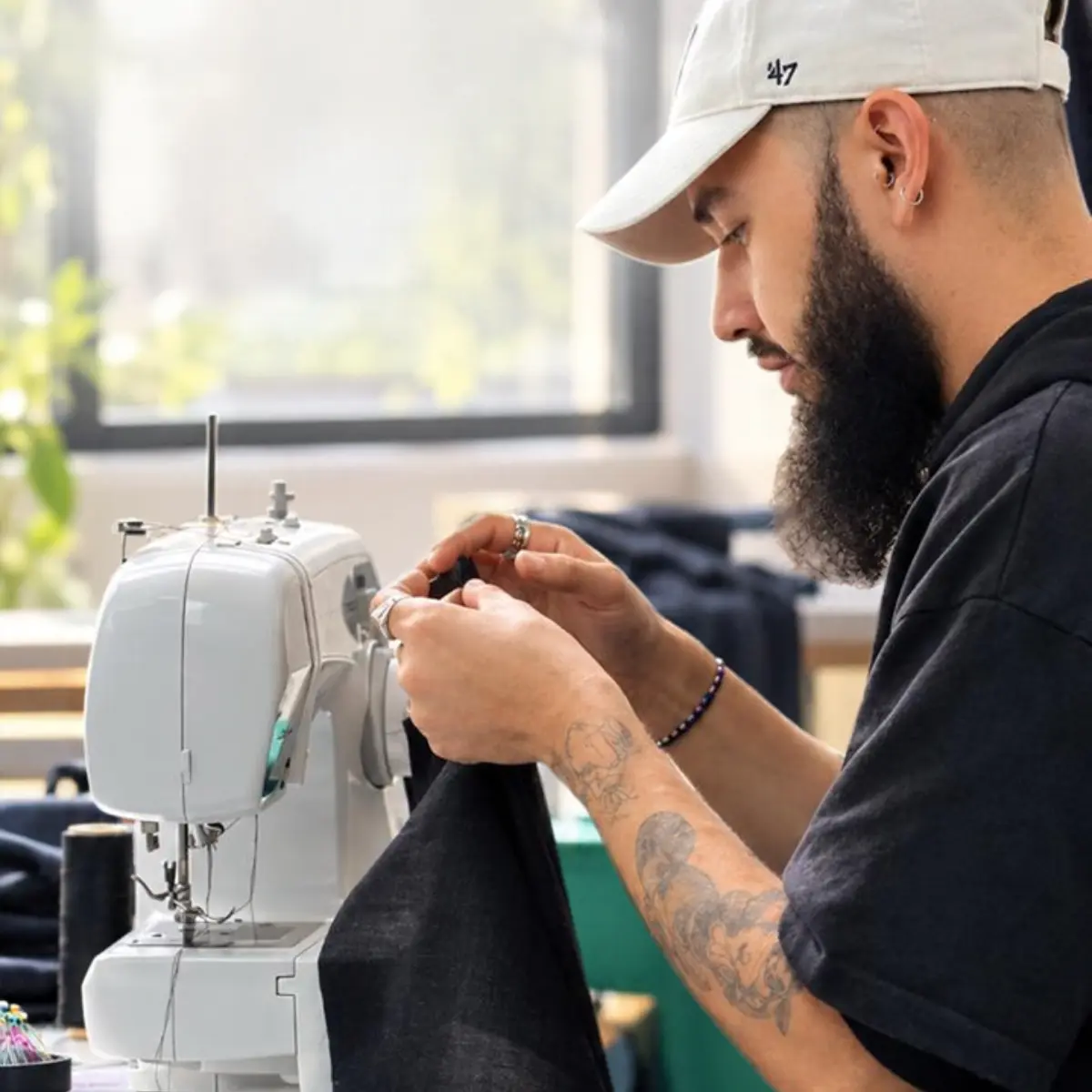 Alumno operando máquina de coser y ensamblando tela oscura durante el Curso Técnicas de Confección 1 en Sistema CyC