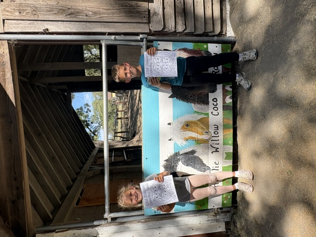 Two children holding Making Mini Memories coloring pages at the name board