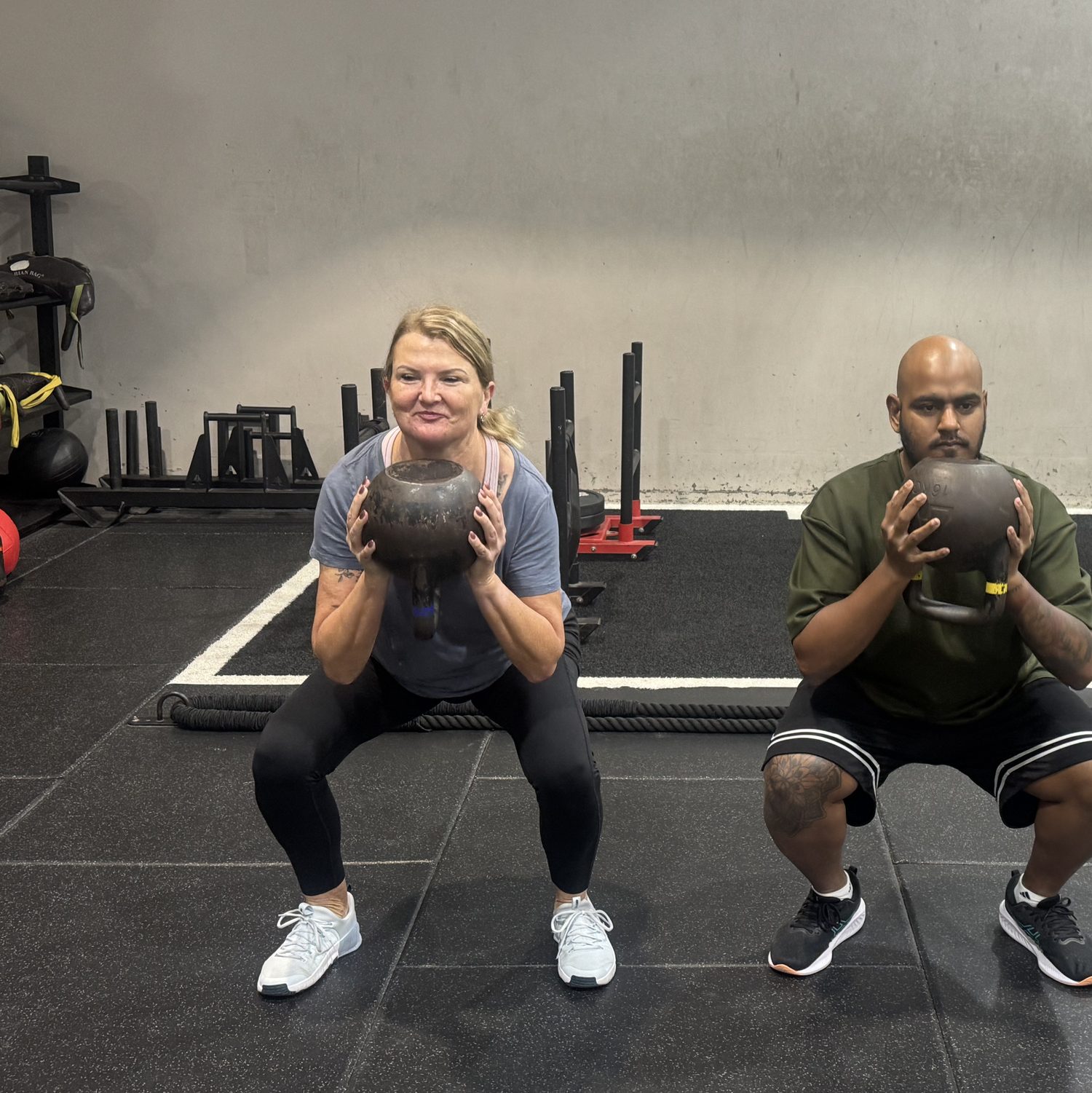 Strength Club members squatting with kettlebells