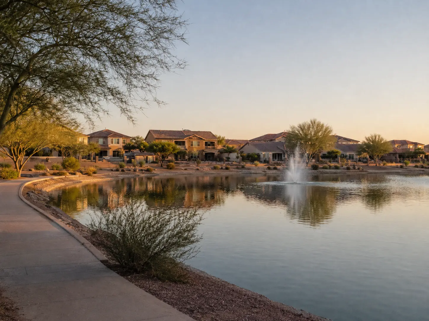 Community lake with fountain and homes at sunset in Maricopa, Arizona