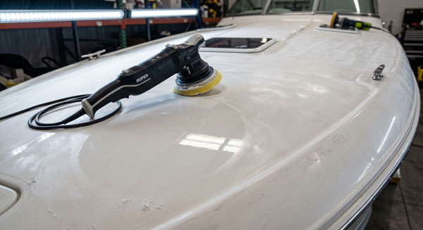 Dual action polisher and marine compound on a boat hull during professional gel coat restoration Dual action polisher and marine compound on a boat hull during professional gel coat restoration