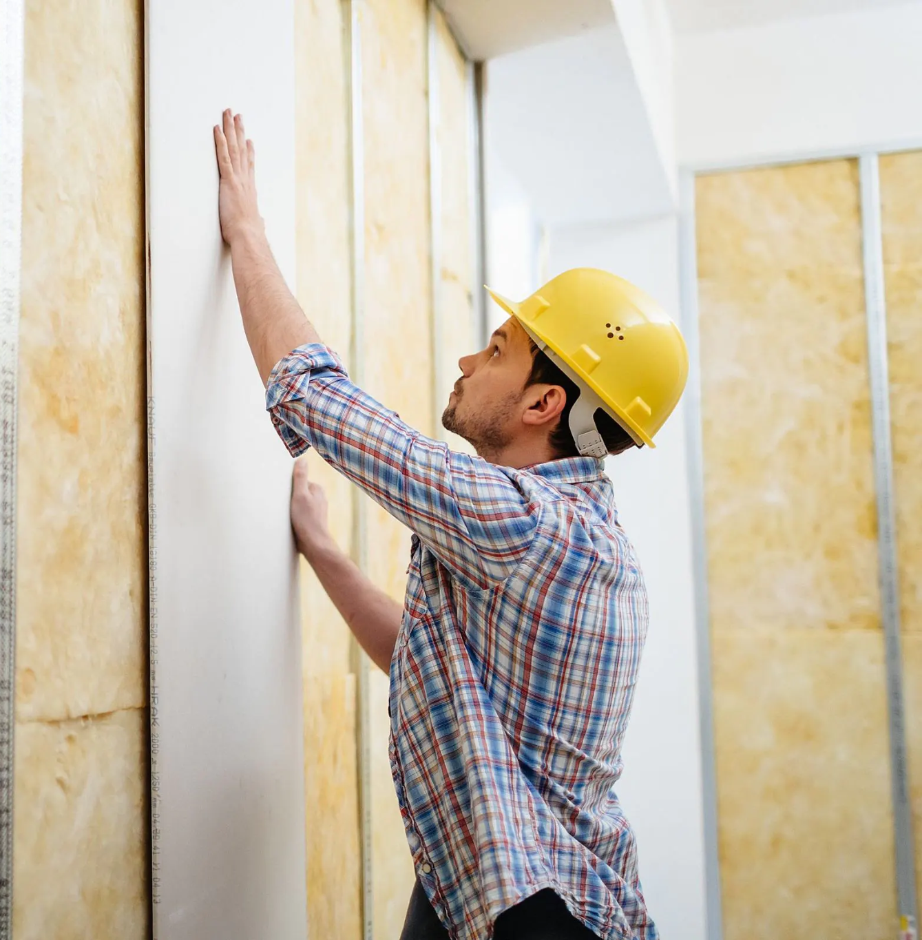 Professional installing drywall inside a building