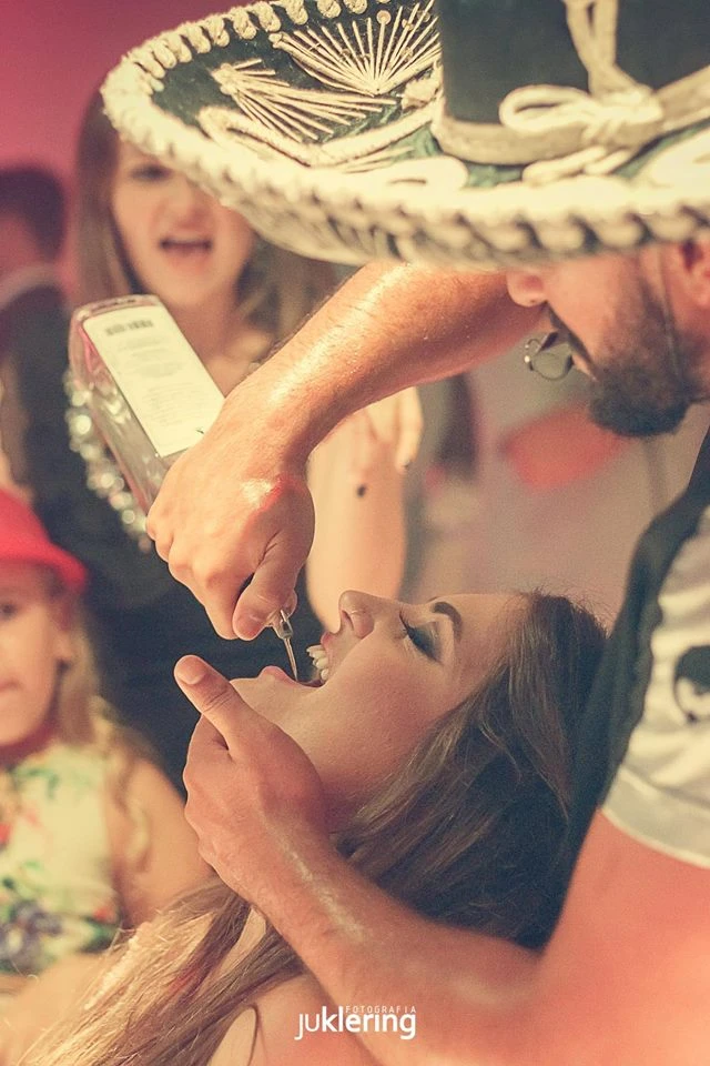 Integrante da equipe com sombrero serve uma bebida a uma convidada na festa