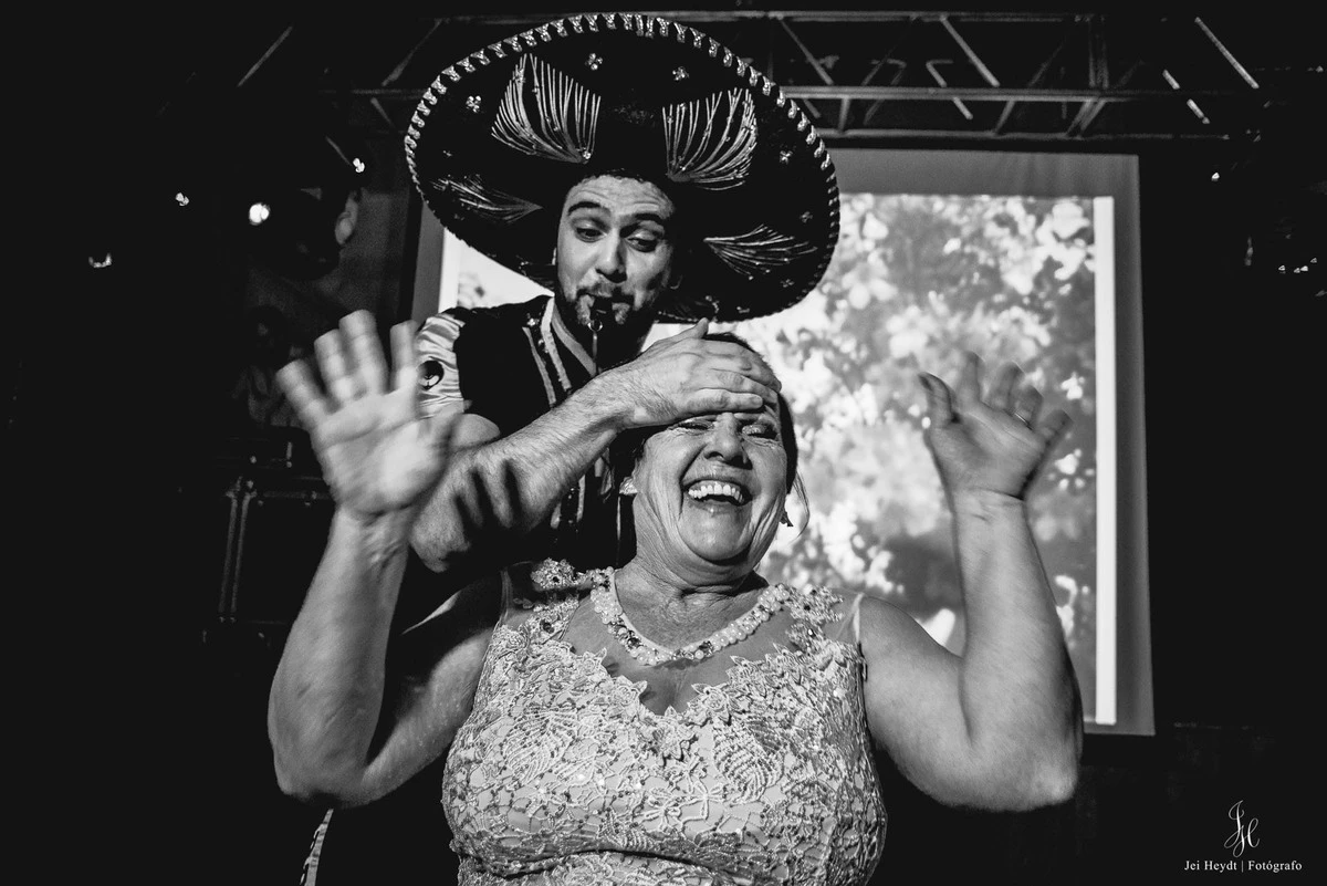 Convidada de vestido bordado levanta as mãos diante de integrante da equipe com sombrero Convidada de vestido bordado levanta as mãos diante de integrante da equipe com sombrero