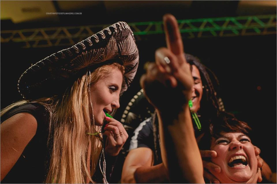 Mulher com sombrero e convidada com o braço levantado durante uma interação na festa Mulher com sombrero e convidada com o braço levantado durante uma interação na festa