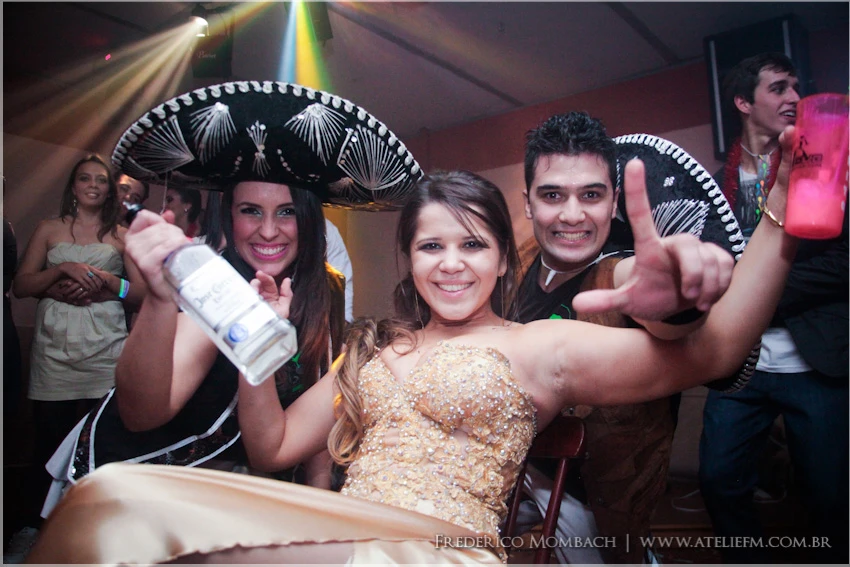 Convidada de vestido dourado posa com integrantes da equipe usando sombreros Convidada de vestido dourado posa com integrantes da equipe usando sombreros
