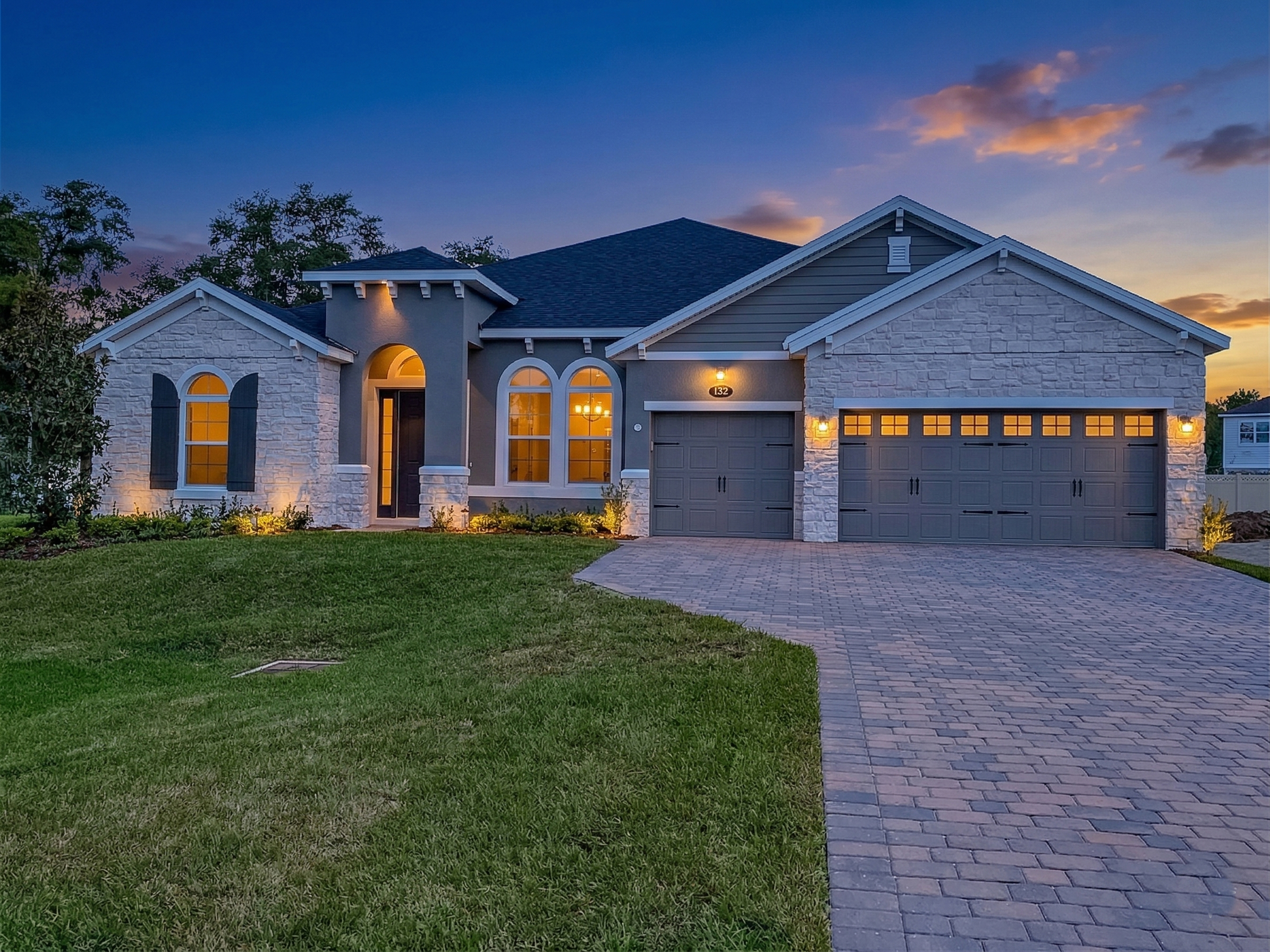 AI-enhanced twilight view of a stone and stucco home with a three-car garage