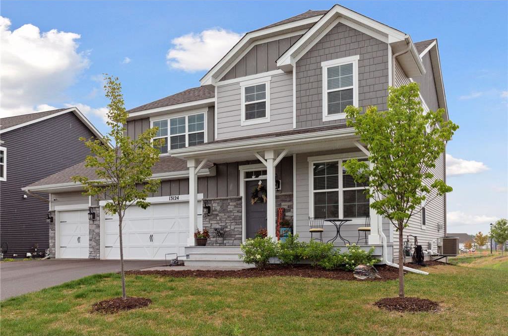 Gray two-story home with a covered front porch, stone accents and a three-car garage.
