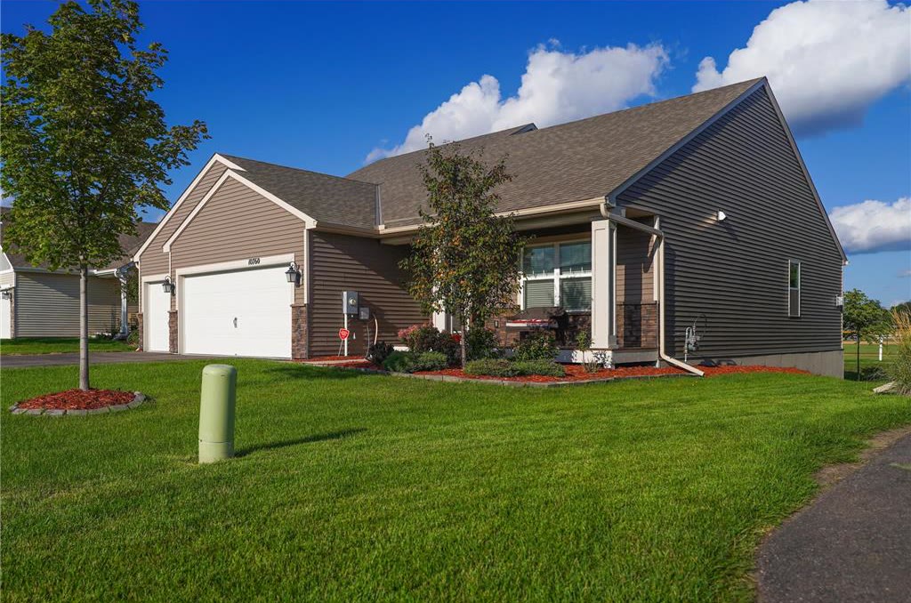 Brown single-level starter home with a two-car garage on a wide green lawn.