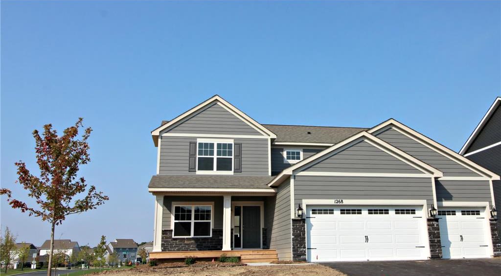 New construction two-story home with a three-car garage under a clear sky.