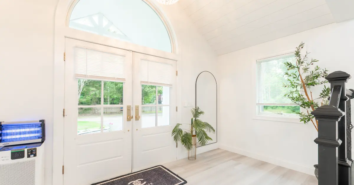 Bright Maine rental property entrance with white double doors and an arched window