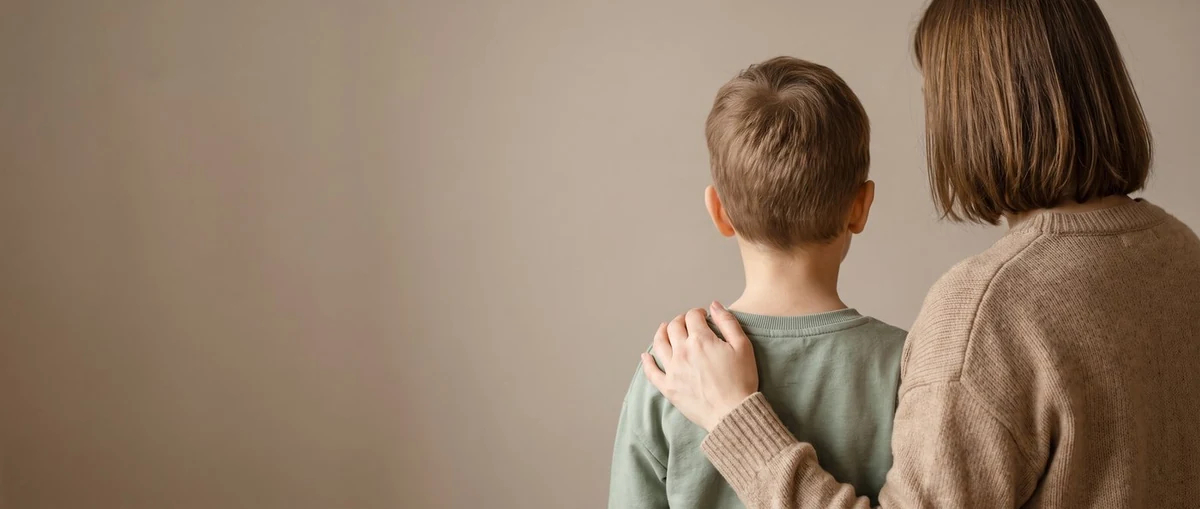 Mutter mit der Hand auf der Schulter ihres Sohnes, von hinten