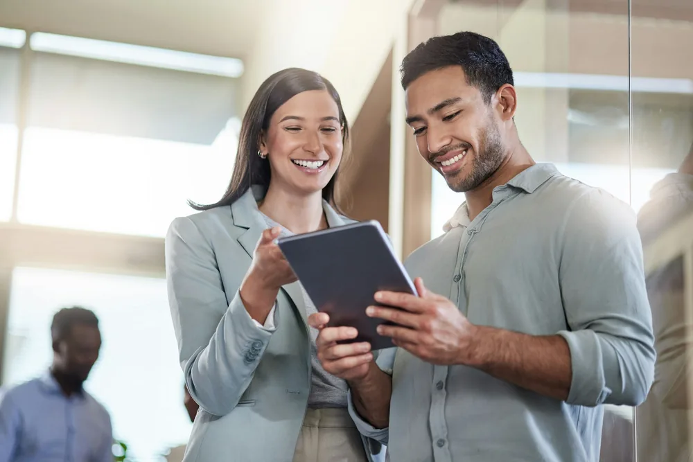 Two coworkers reviewing prescription benefit data on a tablet