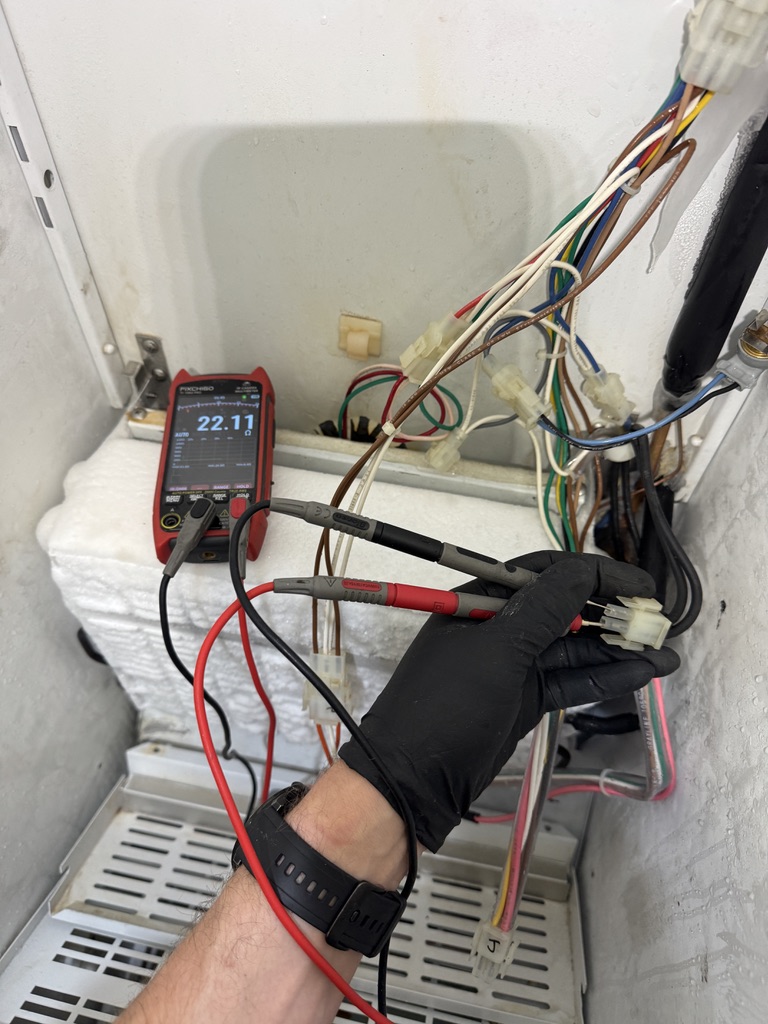 Technician testing the Sub-Zero defrost circuit with a multimeter