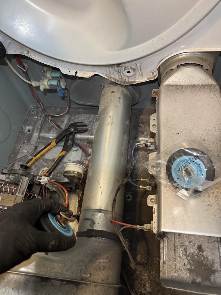 Technician handling a removed Samsung dryer drum roller during replacement
