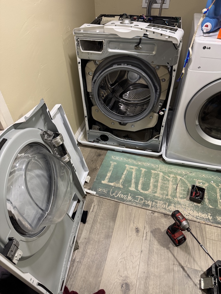 LG front-load washer with the front panel removed for drain pump service