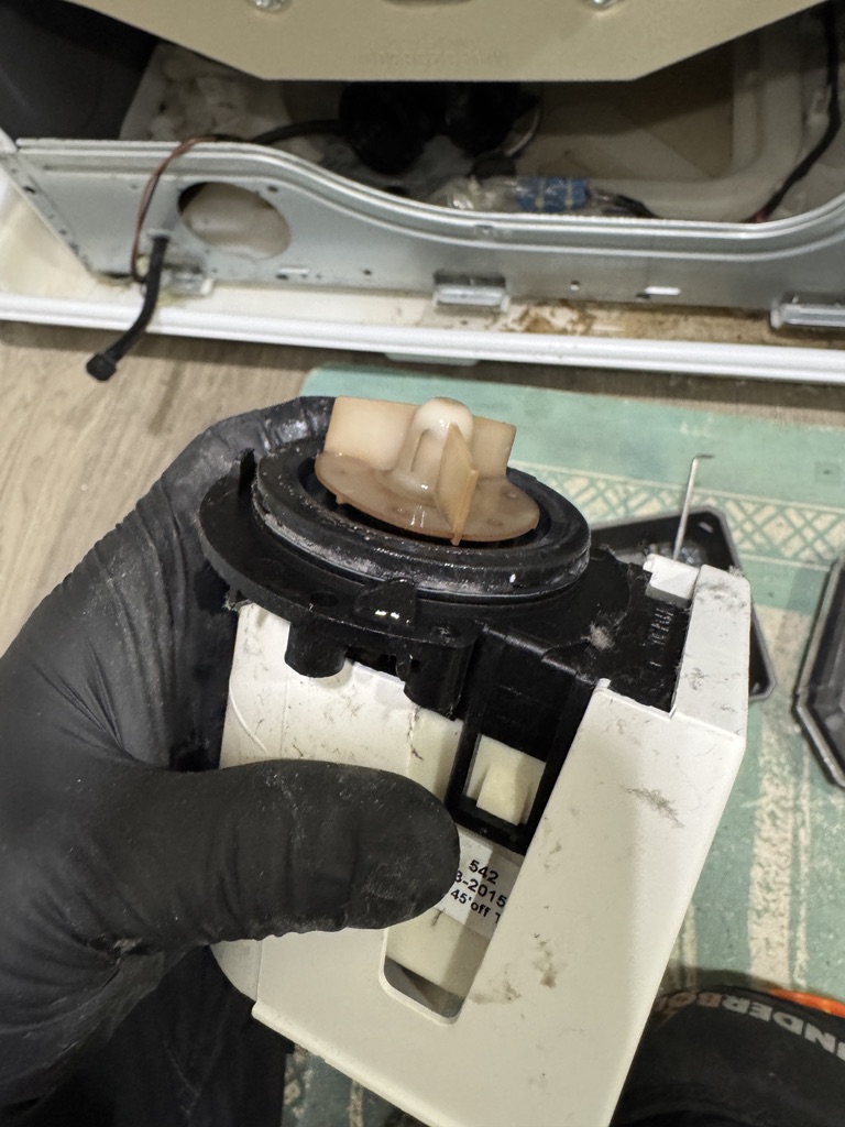 Removed faulty LG washer drain pump and impeller held by a technician