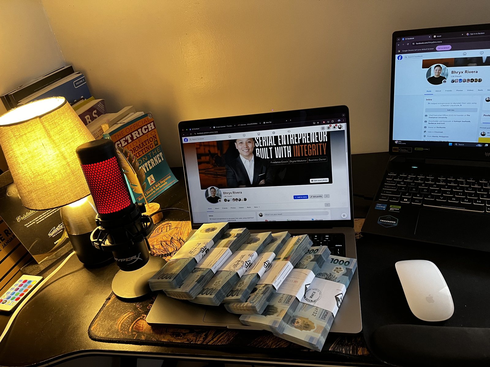 Bhryx's desk: stacks of ₱1,000 bills in front of a laptop showing the Bhryx Rivera Facebook profile