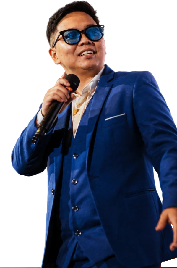 Bhryx Rivera on stage in a blue suit, holding a microphone