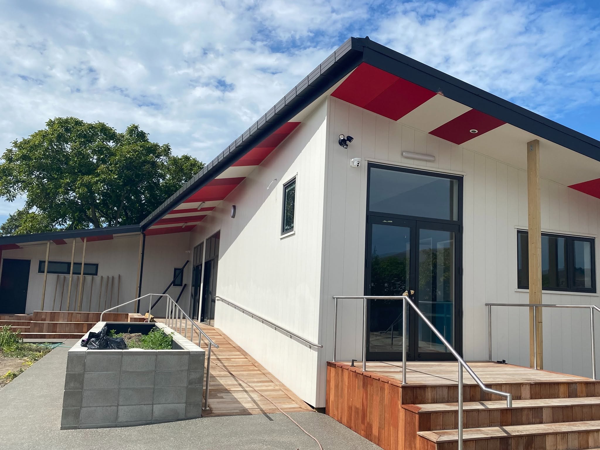 Contemporary Christchurch hillside home with bold red architectural standing-seam upper storey and precision exterior finishes