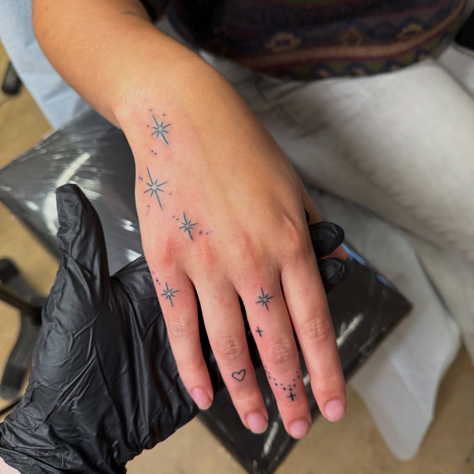 Tiny sparkle stars, dots and a heart spread over the back of the hand and fingers, by Miss Champion