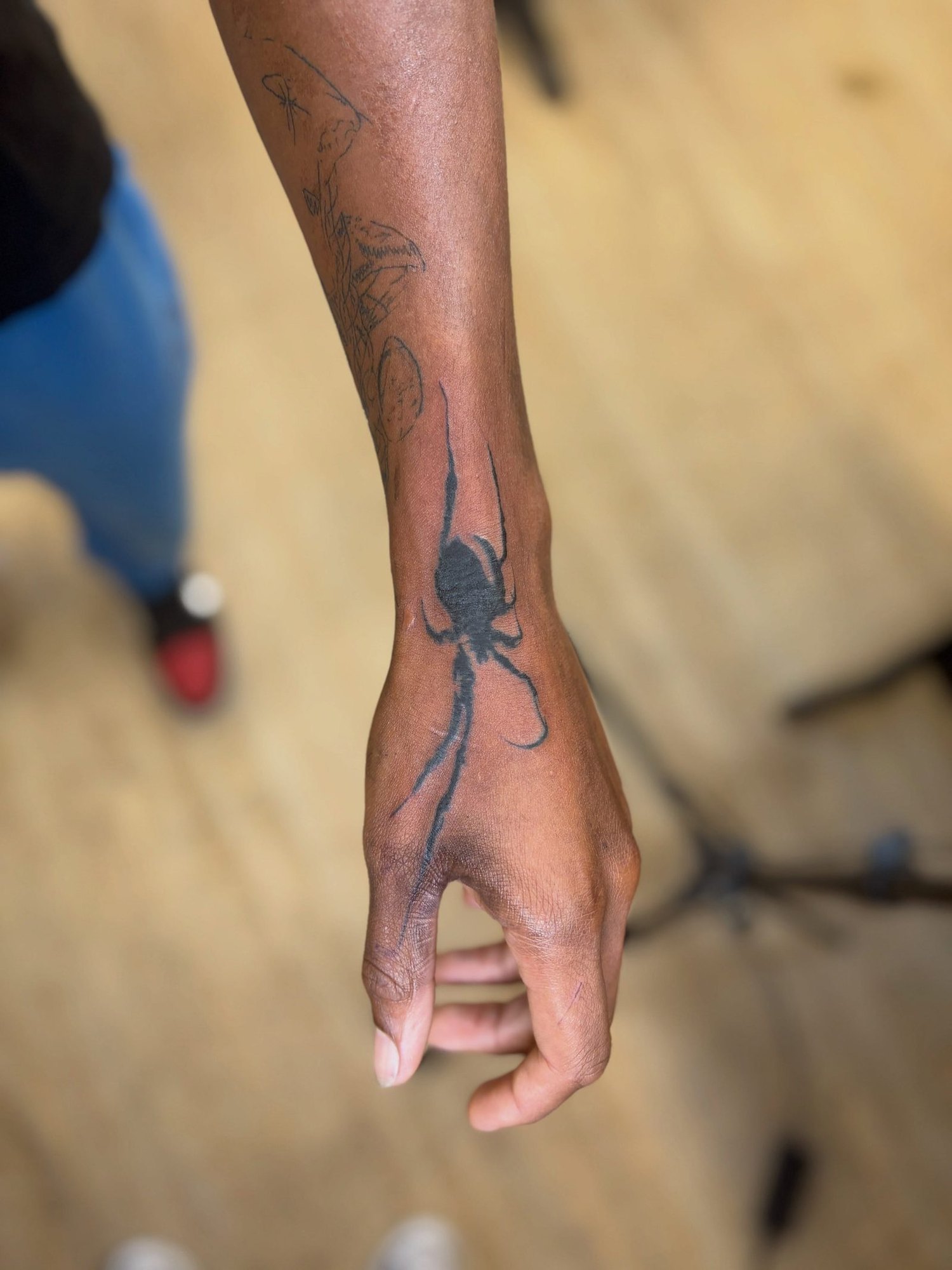 Spider hanging from a thread across the back of the hand and wrist, by Peyton