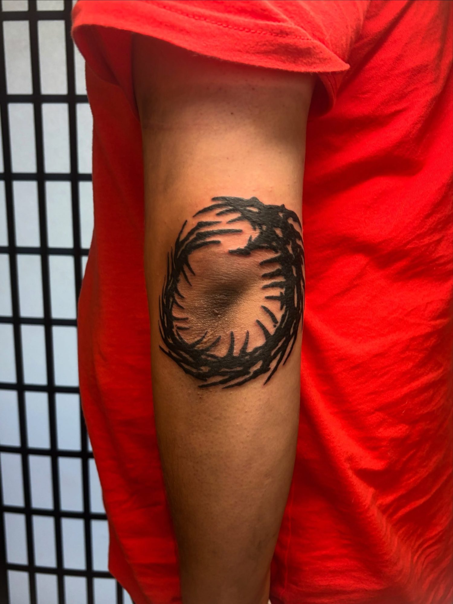 Blackwork ring of thorny branches circling the back of the elbow, by Peyton