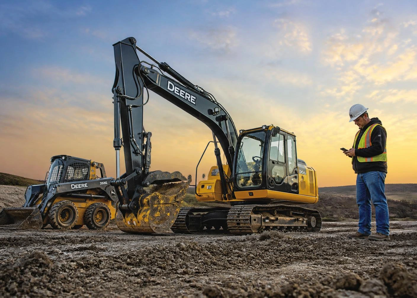 Excavator and skid steer on a construction site with a worker checking his phone