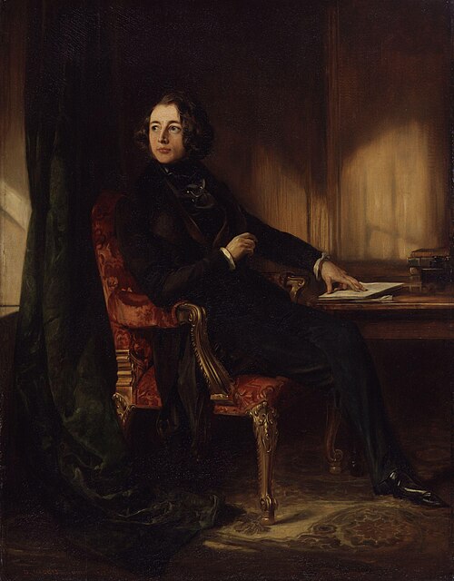 A formal 19th-century painted portrait of a seated man in a richly decorated interior. He is positioned in a red upholstered armchair beside a wooden desk, dressed in dark, elegant clothing typical of the Victorian period. His body is turned slightly to the side while his head looks off to the left, giving a thoughtful, composed expression. One hand rests near papers on the desk, suggesting a literary or professional context. The background features warm tones, a curtain, and ornate detailing, creating a refined and atmospheric setting. A formal 19th-century painted portrait of a seated man in a richly decorated interior. He is positioned in a red upholstered armchair beside a wooden desk, dressed in dark, elegant clothing typical of the Victorian period. His body is turned slightly to the side while his head looks off to the left, giving a thoughtful, composed expression. One hand rests near papers on the desk, suggesting a literary or professional context. The background features warm tones, a curtain, and ornate detailing, creating a refined and atmospheric setting.