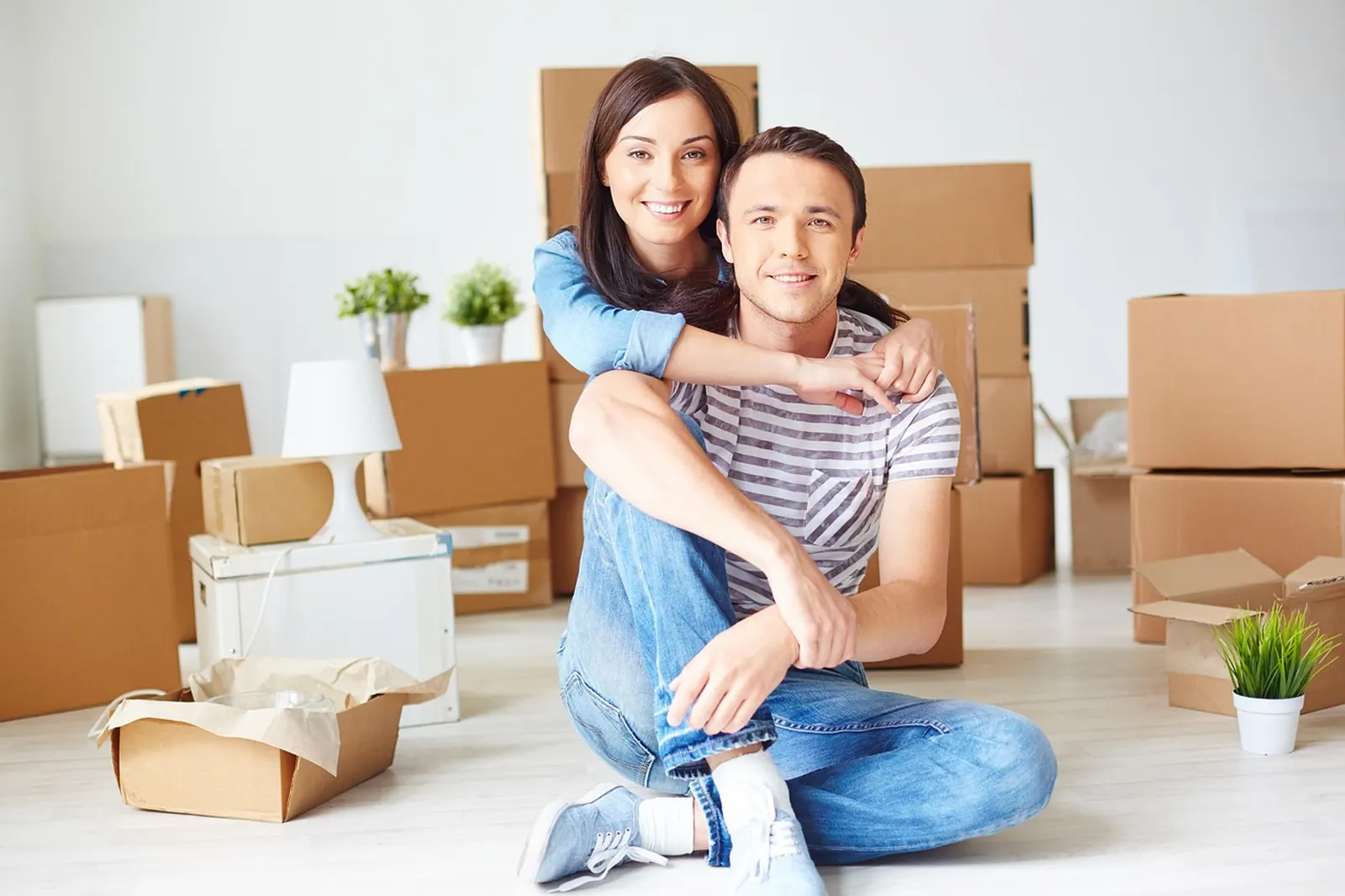 Pareja sentada entre cajas de mudanza en su apartamento, calculando qué tamaño de minidepósito necesita