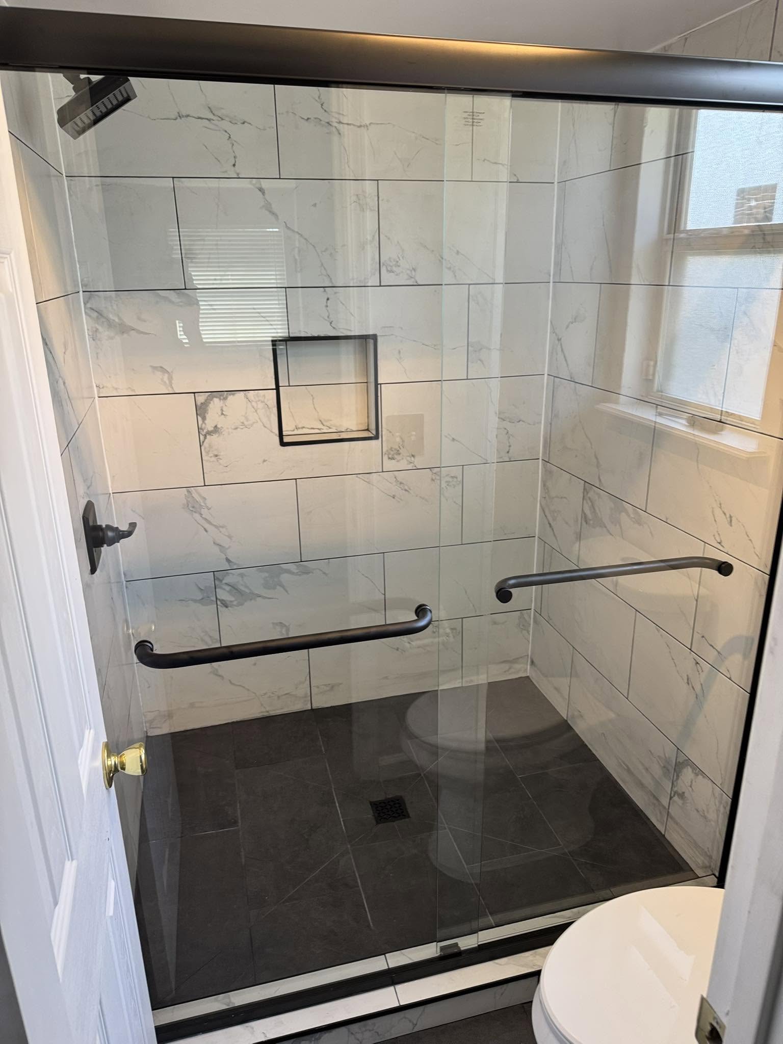 Walk-in shower with glass door and black base