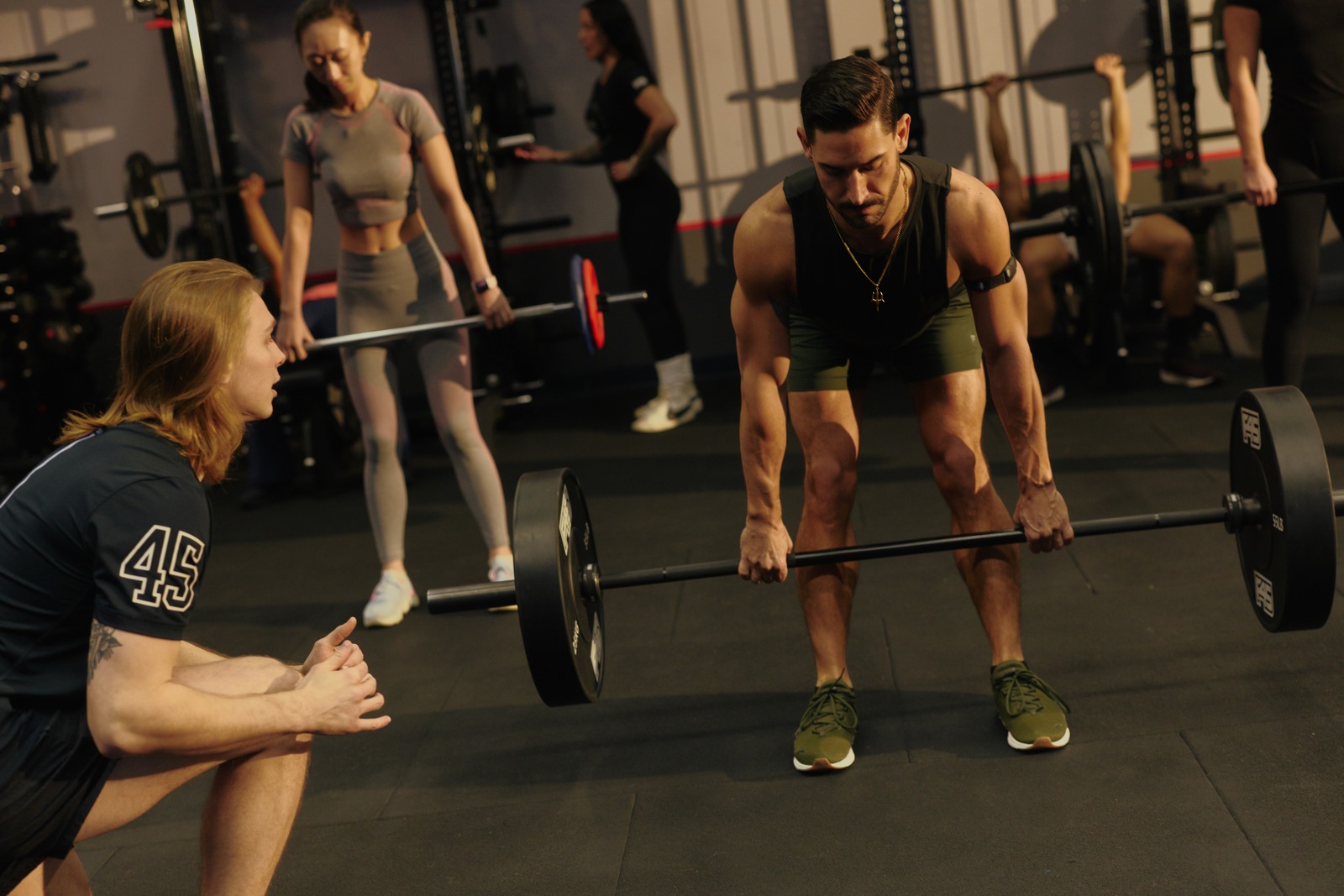 F45 coach talking a member through a barbell deadlift before the workout